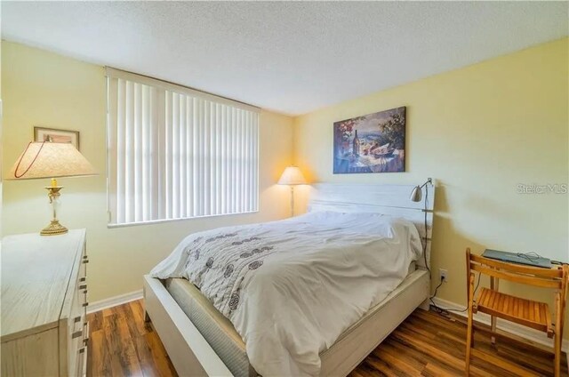 bedroom featuring baseboards, a textured ceiling, and wood finished floors