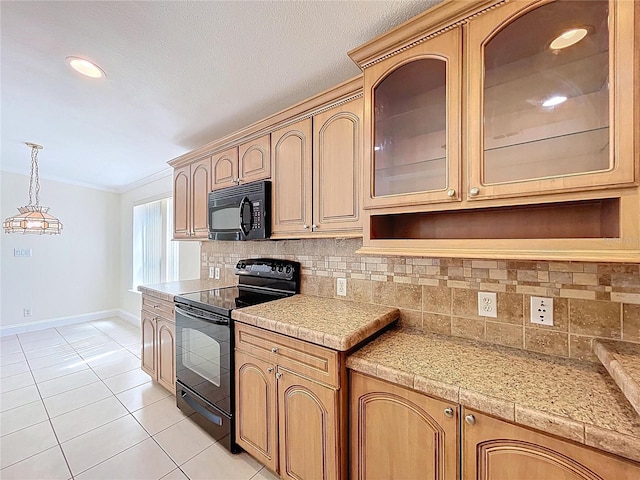 kitchen with glass insert cabinets, light countertops, light tile patterned floors, hanging light fixtures, and black appliances