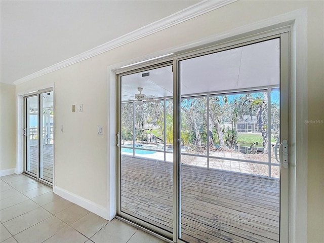 doorway to outside featuring baseboards, a ceiling fan, ornamental molding, and light tile patterned flooring