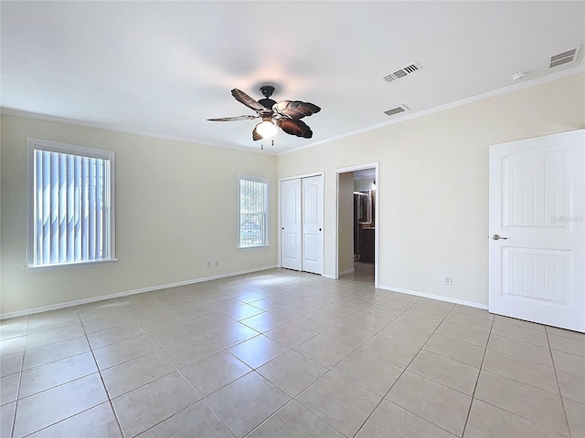 spare room with light tile patterned floors, visible vents, a ceiling fan, and ornamental molding