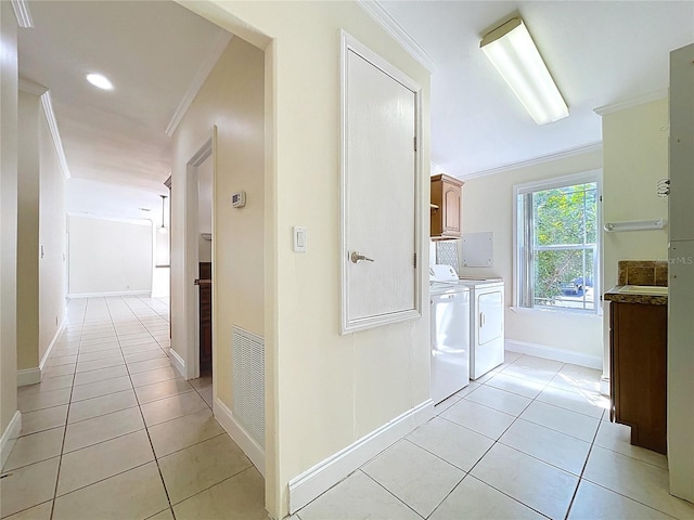 hall with light tile patterned floors, visible vents, independent washer and dryer, and ornamental molding