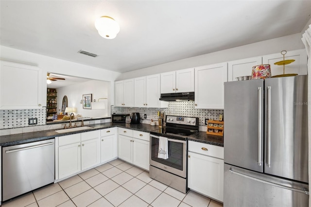 kitchen with visible vents, under cabinet range hood, a sink, tasteful backsplash, and appliances with stainless steel finishes