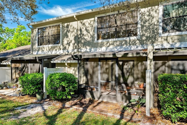 back of property with stucco siding and a sunroom