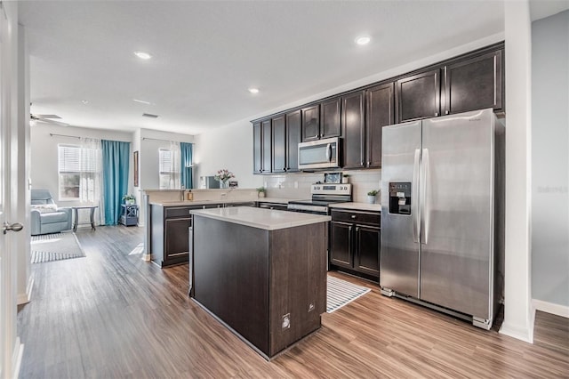 kitchen featuring light countertops, dark brown cabinets, light wood finished floors, and stainless steel appliances