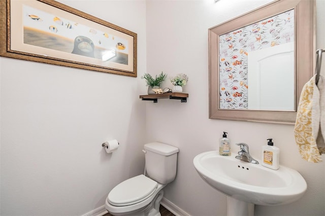 bathroom with toilet, baseboards, and a sink