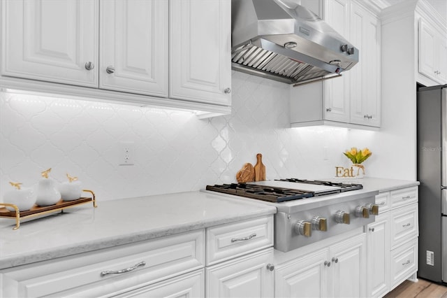 kitchen featuring gas cooktop, tasteful backsplash, white cabinetry, freestanding refrigerator, and extractor fan