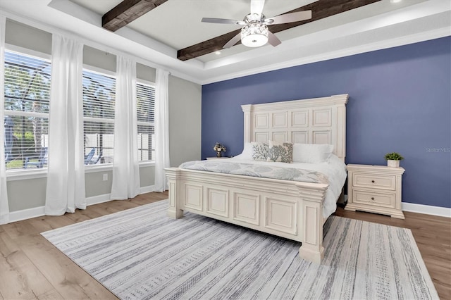 bedroom with beamed ceiling, a ceiling fan, baseboards, and light wood finished floors