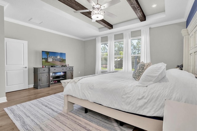 bedroom with ornamental molding, baseboards, a tray ceiling, and wood finished floors