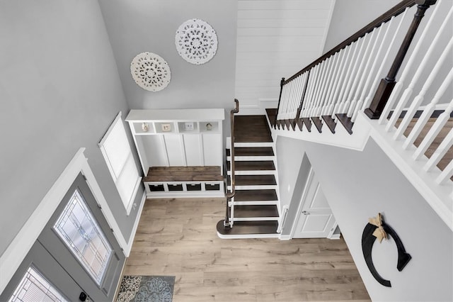 stairway featuring a wealth of natural light, a towering ceiling, and wood finished floors