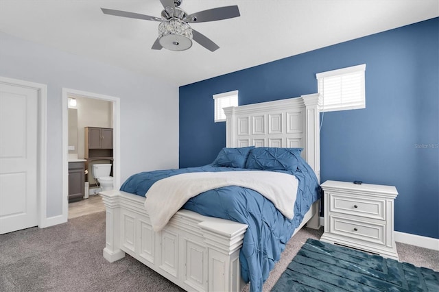 carpeted bedroom featuring ensuite bath, a ceiling fan, and baseboards