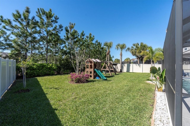 view of yard with a lanai, a fenced backyard, and a playground