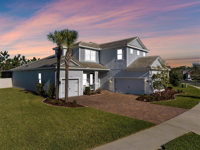 view of front facade with decorative driveway, a lawn, an attached garage, and stucco siding