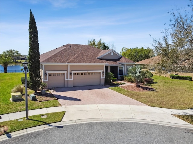 view of front facade featuring driveway, roof with shingles, an attached garage, stucco siding, and a front lawn