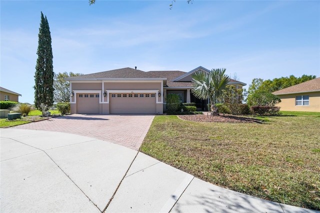 view of front of property with a front lawn, decorative driveway, an attached garage, and stucco siding