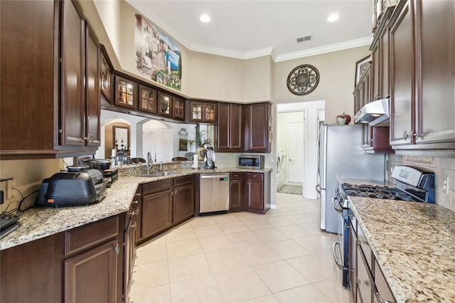 kitchen featuring visible vents, ornamental molding, a sink, under cabinet range hood, and appliances with stainless steel finishes