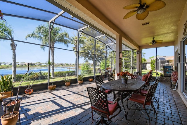 sunroom / solarium with visible vents, ceiling fan, and a water view