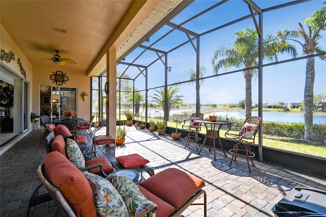 view of patio / terrace with a lanai, a ceiling fan, a water view, and visible vents