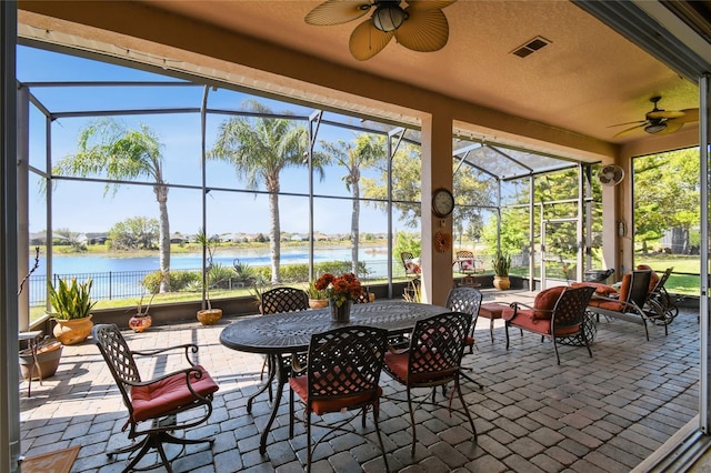 sunroom / solarium with visible vents, a water view, a healthy amount of sunlight, and ceiling fan