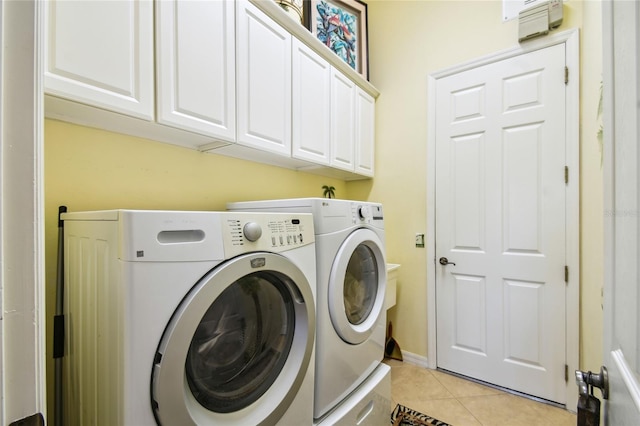 clothes washing area featuring cabinet space, light tile patterned flooring, and washing machine and dryer