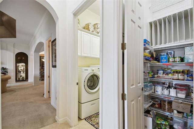 laundry area featuring crown molding, washer / clothes dryer, arched walkways, and light carpet