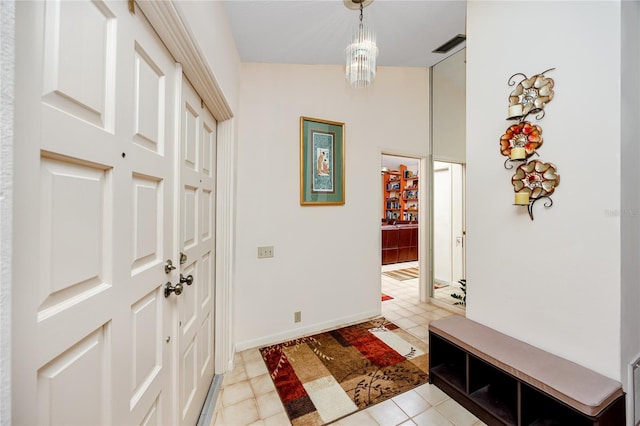 foyer featuring light tile patterned floors, visible vents, baseboards, and vaulted ceiling