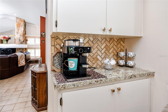 kitchen featuring white cabinetry, lofted ceiling, light tile patterned floors, and backsplash