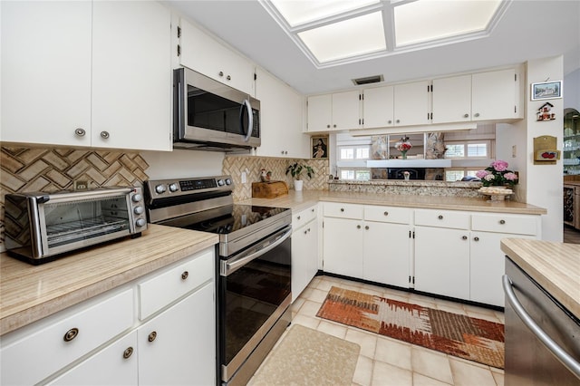 kitchen featuring a toaster, light countertops, decorative backsplash, white cabinets, and stainless steel appliances