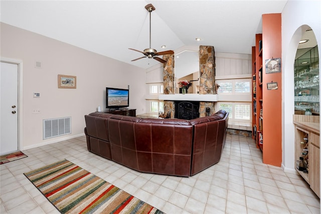 living room featuring visible vents, a stone fireplace, lofted ceiling, and a ceiling fan