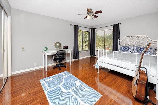 bedroom with wood finished floors, baseboards, and a textured ceiling