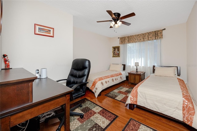 bedroom with a ceiling fan, wood finished floors, and a textured ceiling