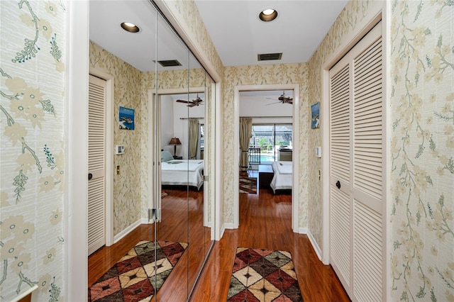 hallway featuring visible vents, baseboards, wood finished floors, and wallpapered walls