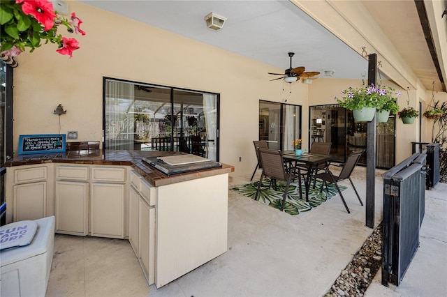 view of patio / terrace featuring outdoor dining area, a ceiling fan, and an outdoor kitchen