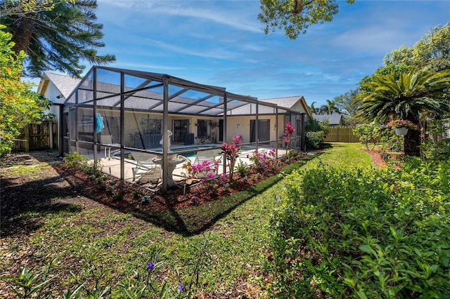 rear view of property featuring a lawn, a patio, a fenced backyard, glass enclosure, and an outdoor pool