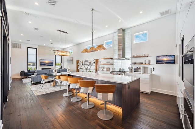 kitchen with dark wood-type flooring, wall chimney exhaust hood, and visible vents