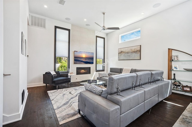 living room with dark wood-style floors, visible vents, a fireplace, and ceiling fan