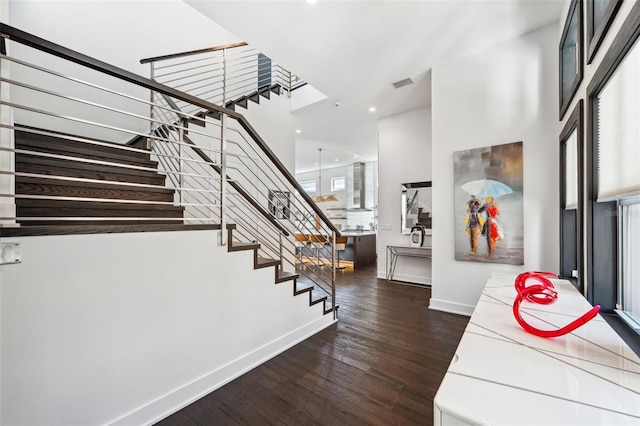 foyer entrance featuring visible vents, dark wood-type flooring, stairway, baseboards, and a healthy amount of sunlight