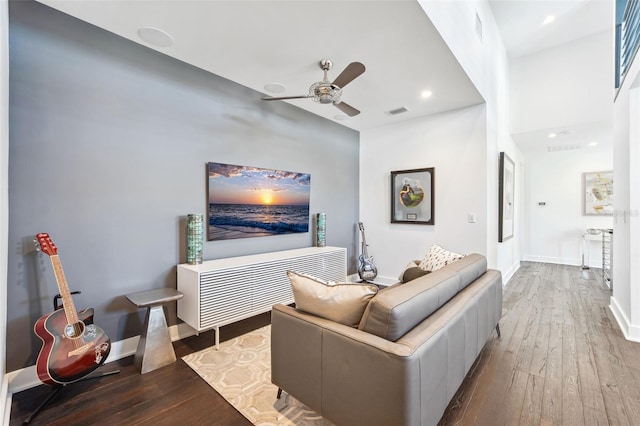 living area featuring hardwood / wood-style floors, a ceiling fan, visible vents, and baseboards