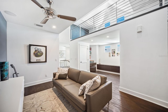 living area featuring hardwood / wood-style floors, visible vents, baseboards, and ceiling fan