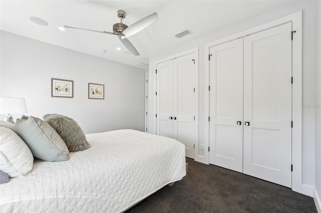 bedroom with a ceiling fan, visible vents, recessed lighting, dark colored carpet, and two closets