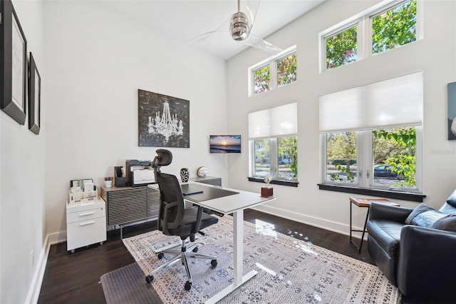 home office featuring baseboards, a high ceiling, and wood finished floors