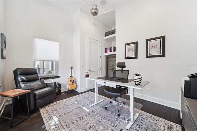 office featuring dark wood-style floors, a high ceiling, and baseboards