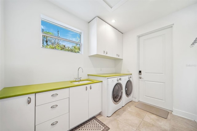 laundry room featuring baseboards, light tile patterned flooring, cabinet space, a sink, and independent washer and dryer