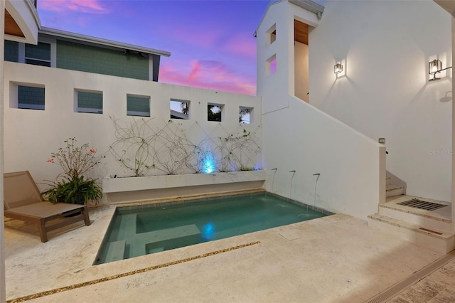 pool at dusk featuring a patio area