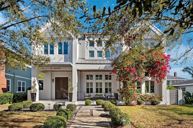 back of property featuring stucco siding, a porch, and a lawn