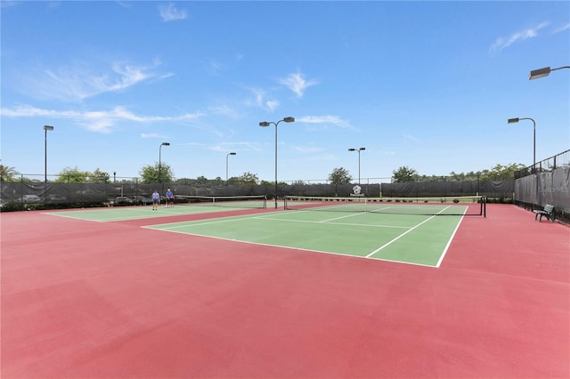 view of tennis court with community basketball court and fence