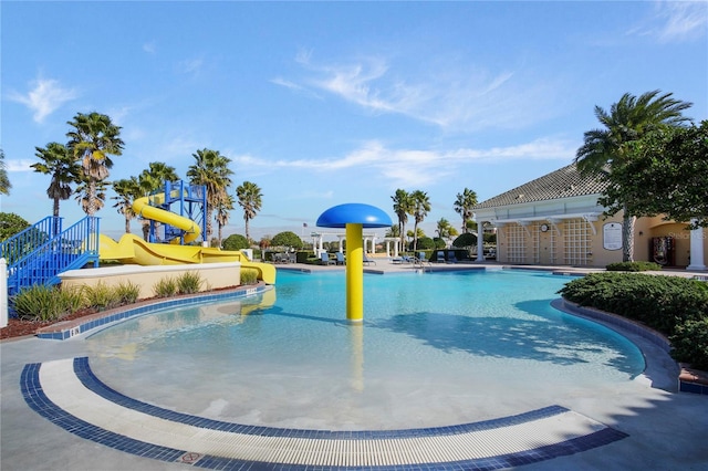 pool featuring a water play area, a water slide, and a patio