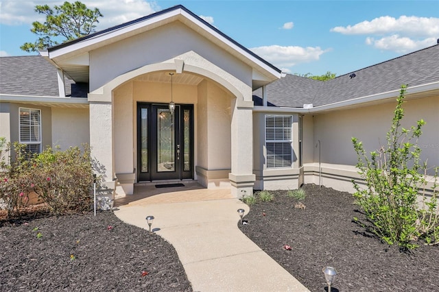 entrance to property with a shingled roof and stucco siding