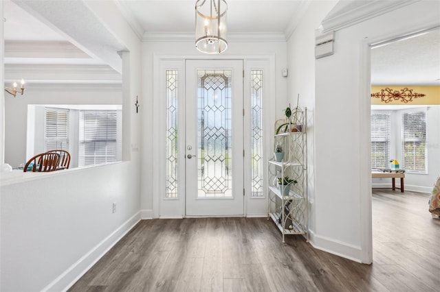 foyer entrance with an inviting chandelier, dark wood-style floors, baseboards, and ornamental molding