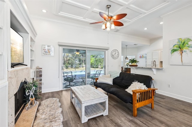 living area with baseboards, ceiling fan, ornamental molding, wood finished floors, and coffered ceiling