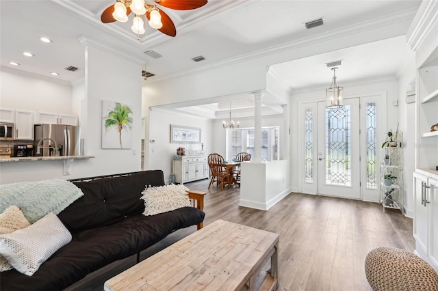 living room with wood finished floors, a healthy amount of sunlight, and ornamental molding